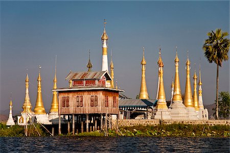 Myanmar, Burma, Lake Inle. A collection of golden stupas, with their 'htis' (umbrella tops) gleaming in the sun, in the middle of Inle Lake. Foto de stock - Direito Controlado, Número: 862-03807987