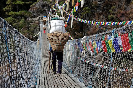 La vallée de Khumbu au Népal, région de l'Everest. Porteurs lourdement chargés traversent le pont suspendu de fil sur l'Everest Base Camp Trek près de Namche Bazar Photographie de stock - Rights-Managed, Code: 862-03808049