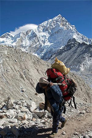 La vallée de Khumbu au Népal, région de l'Everest. Sur les hauteurs de l'Everest Base Camp trail un lourdement chargé et Las porter fait son chemin dans le paysage glaciaire stérile. Photographie de stock - Rights-Managed, Code: 862-03808043