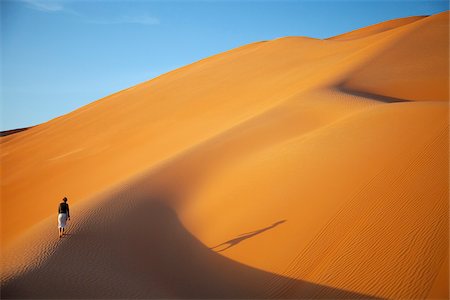 Oman, Empty Quarter. A young lady makes her way up the steep dunes. Stock Photo - Rights-Managed, Code: 862-03808165