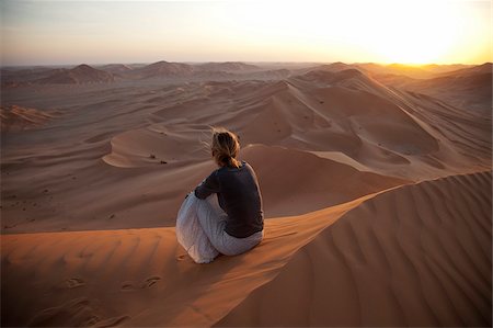 Oman, Empty Quarter. A young lady watches the sun go down over the dunes. Stock Photo - Rights-Managed, Code: 862-03808162