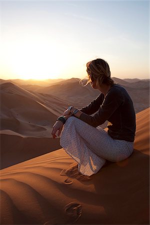 empty quarter desert - Oman, Empty Quarter. Une jeune femme montres le soleil descendre sur les dunes. Photographie de stock - Rights-Managed, Code: 862-03808163