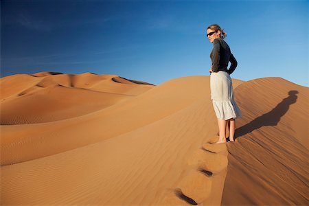 simsearch:862-03808150,k - Oman, Empty Quarter. Oman, Empty Quarter. Une jeune femme debout au sommet d'une dune. Photographie de stock - Rights-Managed, Code: 862-03808170