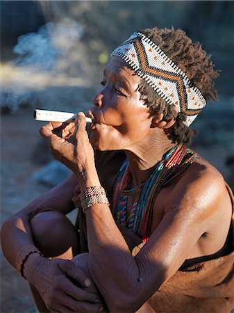 simsearch:862-03807589,k - A woman from the NIIS hunter gatherer band enjoys a smoke. They speak with four distinct click consonants.The NIIS live in the harsh environment of a vast expanse of flat sand and bush scrub country straddling the Namibia Botswana border. Stock Photo - Rights-Managed, Code: 862-03820243