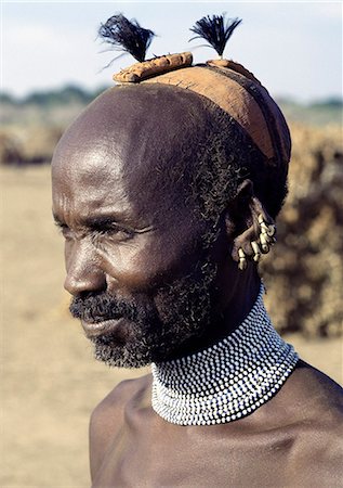 A Dassanech elder wearing a traditional clay hairdo, topped with ostrich feathers. His broad beaded necklace is unusual for its size but his five brass earrings are a common decoration of both men and women.The Dassanech people live in the Omo Delta of southwest Ethiopia, one of the largest inland deltas in the world. Foto de stock - Con derechos protegidos, Código: 862-03820352