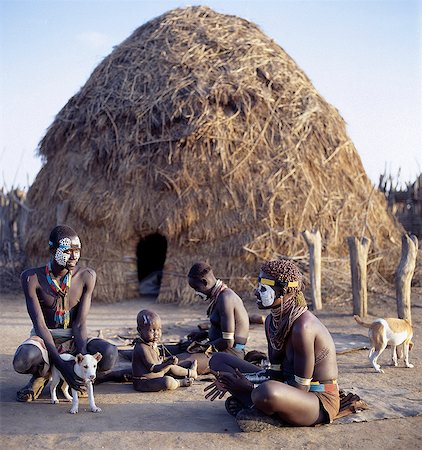 In the late afternoon, family and friends sit outside a high dome roofed Karo home.The Karo excel in body art. Before a dance, they will decorate their faces and torsos elaborately using local white chalk, pulverised rock and other natural pigments. The polka dot or guinea fowl plumage effect is popular. Foto de stock - Con derechos protegidos, Código: 862-03820361