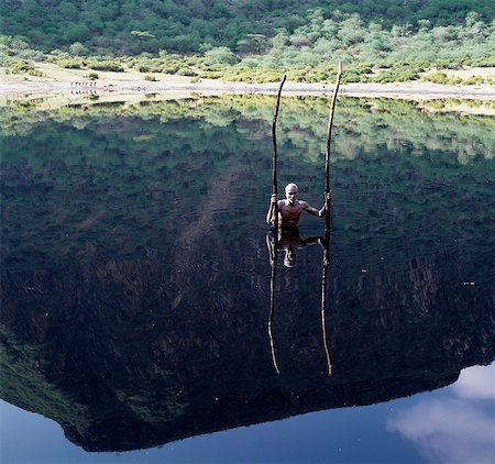 Le volcan éteint à mâcher PARI dans le sud de l'Éthiopie a un lac saisonnier sombre au fond de son cratère face profonde, raide.Des tribus Borana récoltent sel là pour leur bétail.Ils utilisent de longues perches pour arracher les mottes du sel enrichi vase noir d'encre depuis le lit du lac, occasionnellement submerger se rassembler dans leurs bras. Le sel est ensuite transporté à bord du cratère dans les sacoches d'âne. Photographie de stock - Rights-Managed, Code: 862-03820412