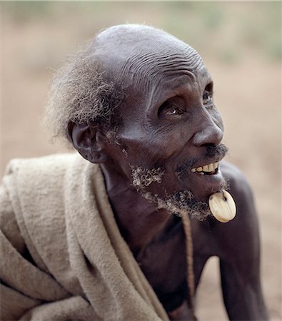 simsearch:862-03820477,k - An old Dassanech man wearing a traditional ivory lip ornament. The old practice of piercing the flesh below a mans lower lip for decorative purposes is fast dieing out.The Dassanech people live in the Omo Delta of southwest Ethiopia, one of the largest inland deltas in the world. Foto de stock - Direito Controlado, Número: 862-03820446