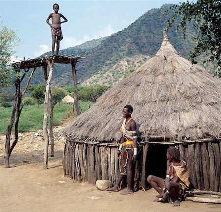 simsearch:862-03820415,k - A thatched house of the Tsemay people of remote Southwest Ethiopia.The girls and women wear attractively decorated leather skirts and aprons, and braid their hair in a number of different eye catching styles.Broad leather shoulder bands decorated with cowrie shells are a common adornment. Foto de stock - Con derechos protegidos, Código: 862-03820448