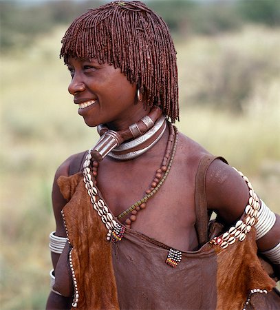 A Hamar woman of Southwest Ethiopia. The phallic protrusion of her necklace denotes that she is her husbands first wife.The Hamar are semi nomadic pastoralists whose richly ochred women have striking styles of traditional dress. Stock Photo - Rights-Managed, Code: 862-03820459