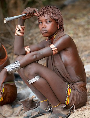 Hamar women dance at a Jumping of the Bull ceremony.The Hamar are semi nomadic pastoralists of Southwest Ethiopia whose women wear striking traditional dress and style their red ochred hair mop fashion. The Jumping of the Bull ceremony is a rite of passage for young men.After the ceremony, the initiate attains full manhood and is permitted to marry. Stock Photo - Rights-Managed, Code: 862-03820519