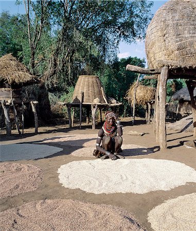 ethiopian tribal braids - A Nyangatom woman dries sorghum and other corn in the vicinity of her elevated grain stores, which prevent loss when the Omo River bursts its banks.The Nyangatom are one of the largest tribes and arguably the most warlike people living along the Omo River in Southwest Ethiopia. Stock Photo - Rights-Managed, Code: 862-03820549