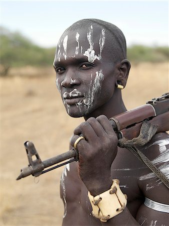 ethiopians tribe with guns - An armed Mursi man wearing a heavy ivory bracelet round his left wrist.The Mursi speak a Nilotic language and have affinities with the Shilluk and Anuak of eastern Sudan. They live in a remote area of southwest Ethiopia along the Omo River. Stock Photo - Rights-Managed, Code: 862-03820570