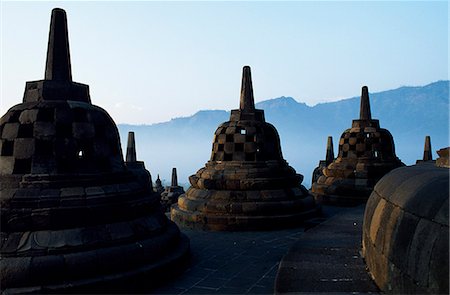 simsearch:862-07910016,k - Grillagees stupas sur les terrasses supérieures, temple de Borobudur, Java, Indonesia.Ranking avec Pagan et Angkor comme l'un des plus grands monuments du sud-est asiatiques, Borobodor, est une énorme construction majestueusement sur une colline surplombant des champs de verdure luxuriantes et les collines lointaines, 42 km au nord-ouest de Yogyakarta. Photographie de stock - Rights-Managed, Code: 862-03820591