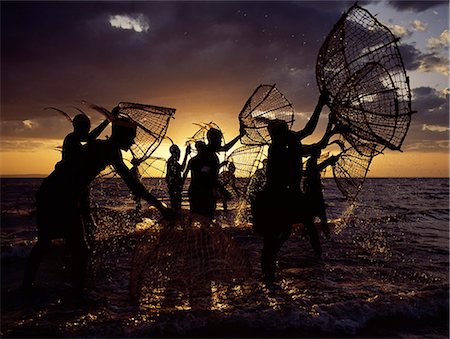 fish workers - As the sun rises over Lake Turkana, a group of fishermen fish for tilapia with their traditional fishing baskets in the lakes shallow waters. These traditional methods of fishing are now rare because the introduction of small mesh gillnets has resulted in a marked decline of fish stocks close to the shore. Stock Photo - Rights-Managed, Code: 862-03820658