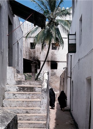 A narrow street in Lamus historic island old town. Most of the buildings standing today were built in the nineteenth century when the island entered its most prosperous period.However, the arrival of Arabs from Oman took place several hundred years earlier and resulted in the development of thriving island states off the East African Coast. Stock Photo - Rights-Managed, Code: 862-03820673