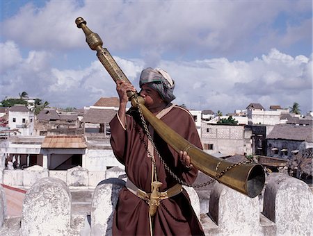 simsearch:862-03731531,k - Un homme de Swahili en habit traditionnel souffle le Siwa sur les remparts de la Borghese.cet de Lamu unique et corne rituel extrêmement lourd a été utilisé avant le XIXe siècle en Pate et Lamu îles herald religieux et festif occasions ou d'alerter la communauté du danger. Photographie de stock - Rights-Managed, Code: 862-03820714