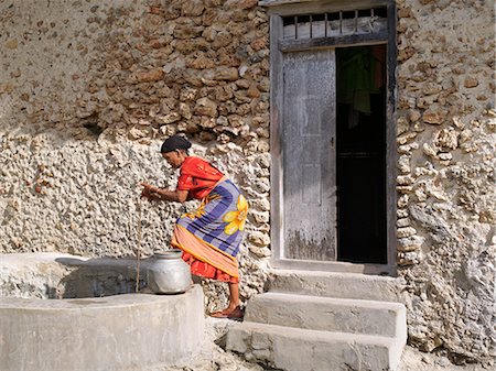 simsearch:862-03365006,k - An old woman draws brackish water from a well outside her home in Faza village. Her house, like most others in the village, is made of coral rag.The chequered history of Faza dates back several hundred years. Foto de stock - Con derechos protegidos, Código: 862-03820741