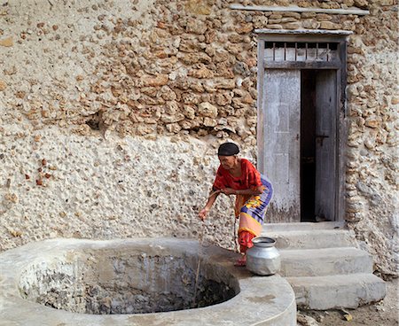 simsearch:862-03820754,k - An old woman draws brackish water from a well outside her home in Faza village. Her house, like most others in the village, is made of coral rag.The chequered history of Faza dates back several hundred years. Stock Photo - Rights-Managed, Code: 862-03820742