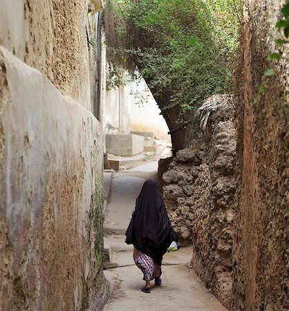 A Swahili woman dressed in black to signify her Muslim faith walks through the narrow streets of Lamu town. Situated 150 miles north northeast of Mombasa, Lamu town dates from the 15th century AD. The islands importance lies in the fact that it has the only certain source of sweet groundwater in the entire district. Stock Photo - Rights-Managed, Code: 862-03820765