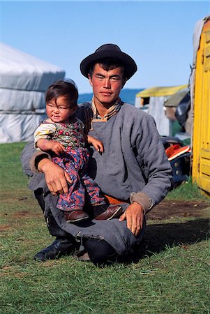 Mongolia, Khentii Mountains, north west of Ulan Bator, Mongolian man with child.The Khentii mountains are under 2,000m and are thickly forested and well watered.The watershed of three huge drainage basins, the Arctic Ocean, the Pacific Ocean and the inland basin of Central Asia, come together at Chandmani Mountain in Khentii Province. Stock Photo - Rights-Managed, Code: 862-03820859