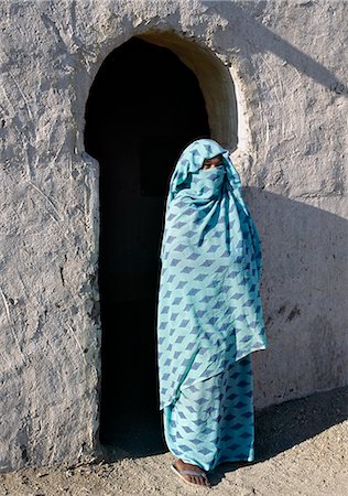 A Nubian woman, her face covered by her headscarf to denote her Muslim belief, stands outside the verandah of her home.The style of verandah arch is typical of the Nubian people. Stock Photo - Rights-Managed, Code: 862-03820976