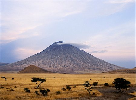 Ol doinyo Lengai, the Maasais Mountain of God, in early morning sunlight. It is the only active volcano in the Gregory Rift.An important section of the eastern branch of Africas Great Rift Valley.This 9,400 foot high volcano with deeply eroded sides stands 7,000 feet above the surrounding plains. Stock Photo - Rights-Managed, Code: 862-03821010
