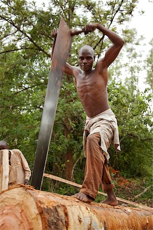 simsearch:862-03887439,k - Burundi. Un homme coupe un arbre en planches dans une fosse de sciage traditionnel. Photographie de stock - Rights-Managed, Code: 862-03887457