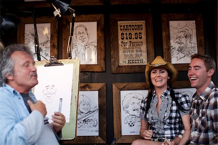rodeo - A young couple getting their caricture done by an artist at the Calgary Stampede, Canada Fotografie stock - Rights-Managed, Codice: 862-03887480