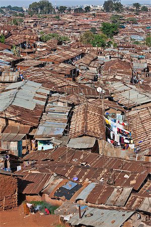 slum birds eye view - Kibera is the biggest slum in Africa and one of the largest in the world. It houses about one million people in cramped, unhygienic conditions on the outskirts of Nairobi. Modern high-rise buildings of the city centre are visible in the distance. Foto de stock - Con derechos protegidos, Código: 862-03888771