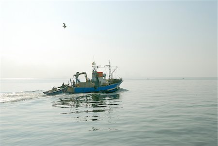 Fishing boat in a foggy morning going to the sea. Setubal, Portugal Fotografie stock - Rights-Managed, Codice: 862-03889024