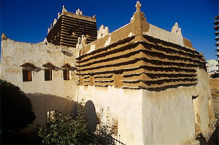Saudi Arabia, Asir, Abha. Built in around 1927 for a local governor, the Shada Palace is a fine example of one of the region's traditional forms of architecture (sometimes called raqaf) where adobe walls (khulb) are protected from erosion by projecting courses of schist (raqaf). Foto de stock - Con derechos protegidos, Código: 862-03889534
