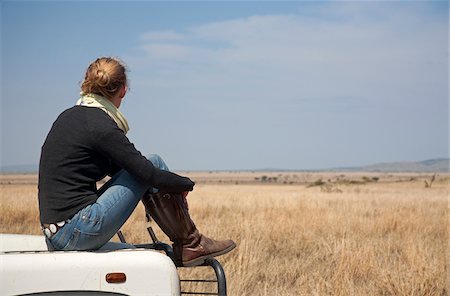sitting car hood - Tanzania, Serengeti. A woman looks out over the Serengeti plains from the bonnet of her Land Rover. Stock Photo - Rights-Managed, Code: 862-03890066
