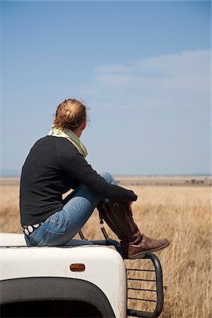 sitting car hood - Tanzania, Serengeti. A woman looks out over the Serengeti plains from the bonnet of her Land Rover. Stock Photo - Rights-Managed, Code: 862-03890067