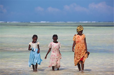A woman and two children walking along the shallow water of the Indian Ocean in Zanzibar, Tanzania Stock Photo - Rights-Managed, Code: 862-03890080