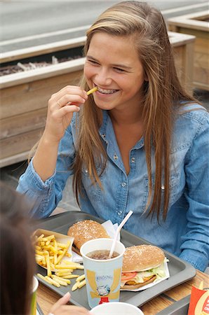 restaurant burger - Teenage girl wearing a dental brace, eating an hamburger with french fries Stock Photo - Rights-Managed, Code: 877-06835674