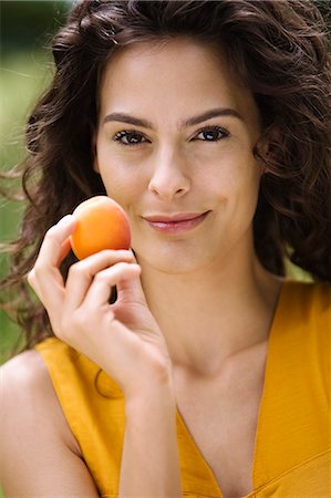 simsearch:6108-05862422,k - Portrait of a young woman holding an apricot Foto de stock - Con derechos protegidos, Código: 877-06832192