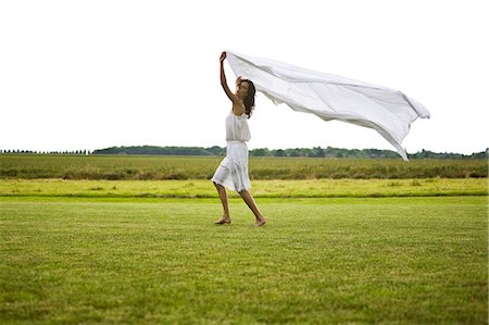 simsearch:877-08129361,k - Young woman walking and holding a white sheet, oudoors Fotografie stock - Rights-Managed, Codice: 877-06832351