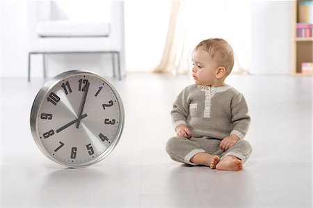 reloj de sol - Baby looking at clock on floor Photographie de stock - Rights-Managed, Code: 877-06832381