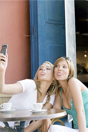 sacando la lengua - Two young women taking a self portrait with mobile, outside Foto de stock - Con derechos protegidos, Código: 877-06832529