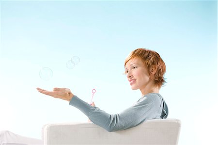 simsearch:877-06832874,k - Portrait of woman on light blue background, playing with bubbles Fotografie stock - Rights-Managed, Codice: 877-06832878