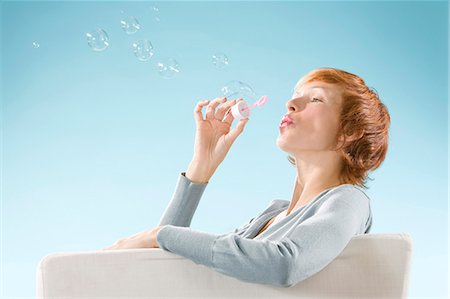 simsearch:877-06832874,k - Portrait of woman on light blue background, playing with bubbles Fotografie stock - Rights-Managed, Codice: 877-06832879