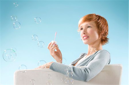 simsearch:877-06833387,k - Portrait of woman on light blue background, playing with bubbles Stock Photo - Rights-Managed, Code: 877-06832880