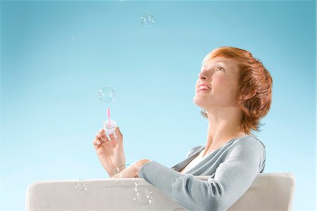 simsearch:877-06832874,k - Portrait of woman on light blue background, playing with bubbles Fotografie stock - Rights-Managed, Codice: 877-06832881