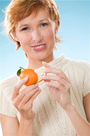 simsearch:877-06832874,k - Portrait of woman peeling a clementine Fotografie stock - Rights-Managed, Codice: 877-06832931