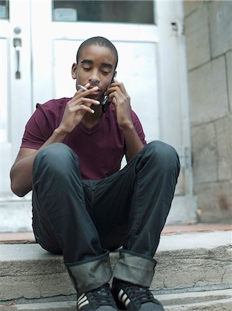 Teenage boy smoking while phoning Stock Photo - Rights-Managed, Code: 877-06833927