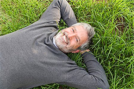 Mature man smiling laying on the grass Photographie de stock - Rights-Managed, Code: 877-07460419