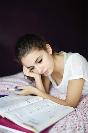 school objects - A teenage girl doing homework on her bed Stock Photo - Rights-Managed, Code: 877-08031279