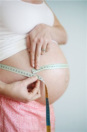 A seven months pregnant woman measuring her round belly Stock Photo - Rights-Managed, Code: 877-08031289