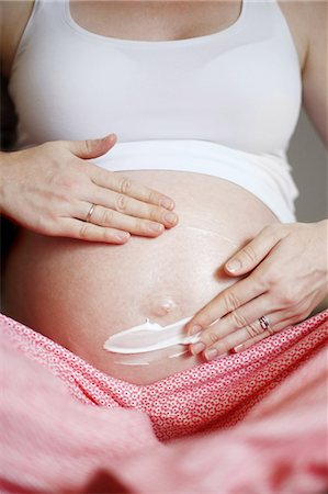 7 months pregnant woman puting cream on her round belly Stockbilder - Lizenzpflichtiges, Bildnummer: 877-08031291